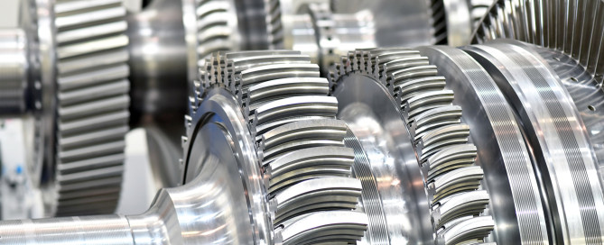 Close-up view of large metal gears and turbine components with precise, shiny teeth.