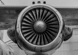 A close-up black and white image of an aerospace jet engine's turbine blades and outer casing, viewed from the front.
