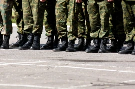 Soldiers standing in formation on a paved area, wearing camouflage uniforms and black boots, resemble the disciplined precision often seen in various industries.