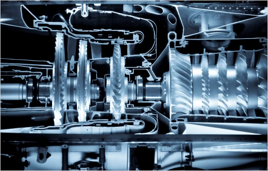 Close-up of a complex turbine engine cross-section showing various gears, blades, and internal components in a high contrast, blue-toned image.