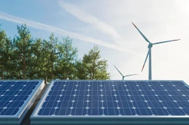 Solar panels with trees and wind turbines in the background illustrate the harmonious blend of industries under a clear sky.