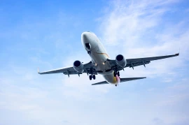 A commercial airplane approaches for landing against a blue sky with scattered clouds, showcasing the marvels of the aviation industries.