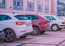 Four cars of different colors, showcasing the latest in transportation technology, are parked in a row within an urban setting.
