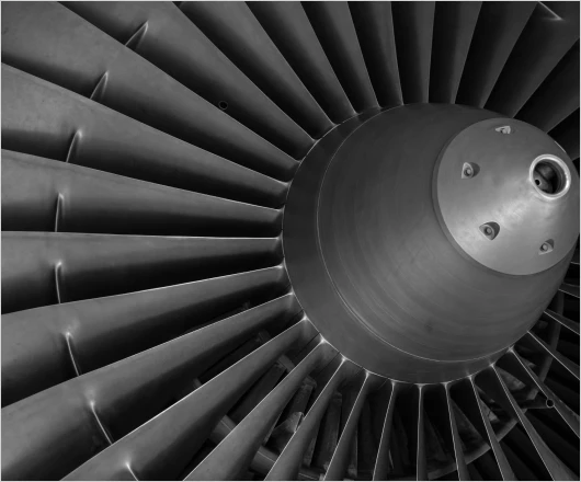 Close-up image of a jet engine turbine with metal blades fanning out in a circular pattern, showcasing the intricate engineering of turbomachinery development.