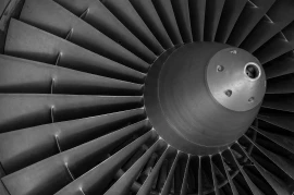 Close-up of a jet engine turbine, showcasing a series of dark, radially arranged blades in focus—a testament to expert turbomachinery development.