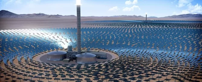 Aerial view of a solar power plant with numerous solar panels surrounding a central tower in a desert landscape under a blue sky.