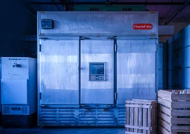 An industrial stainless steel freezer, incorporating advanced refrigeration technology, is surrounded by wooden crates and machinery in a bustling warehouse setting.