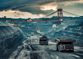 A large mining operation with trucks transporting materials in a deep open pit, guided by advanced HVAC technology. An overhead conveyor cuts through dark clouds in the background, highlighting the industry's reliance on innovative climate control solutions.