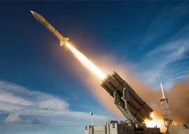 A missile launches into a clear blue sky from a military platform, leaving a trail of smoke and fire, showcasing the precision and power integral to government defense strategies.