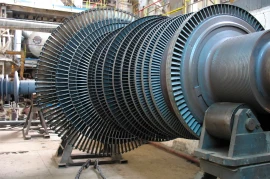 Large industrial turbine with multiple metal blades, installed in a factory setting, showcasing the cutting-edge of turbomachinery development.