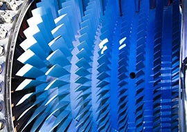 Close-up view of blue turbine blades arranged in a circular pattern inside an aerospace engine.