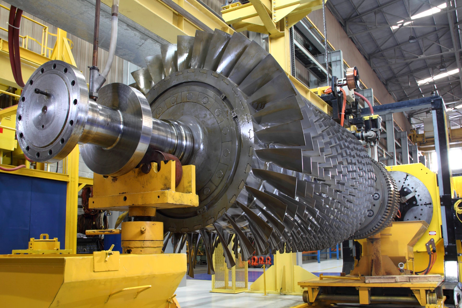 Large industrial turbine in a factory setting with yellow and blue machinery surrounding it.