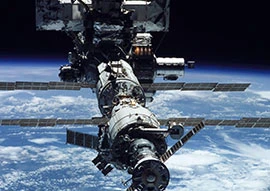 A spacecraft equipped with advanced space technology and solar panels orbits above Earth, offering a breathtaking view of the planet's curvature and shimmering atmosphere.